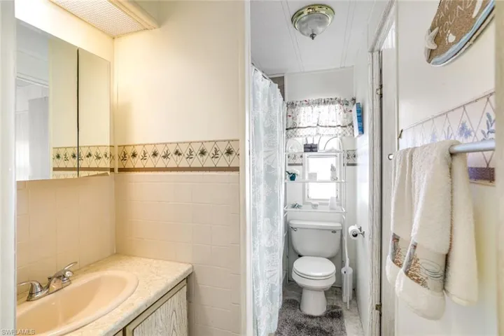 Full bathroom featuring vanity, a shower with shower curtain, a wainscoted wall, and tile walls