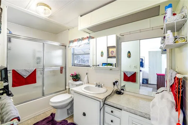 Full bathroom featuring vanity, combined bath / shower with glass door, light tile patterned floors, and tile walls
