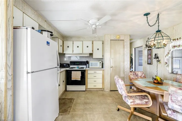 Kitchen with white appliances, light countertops, ceiling fan, and suspended lighting
