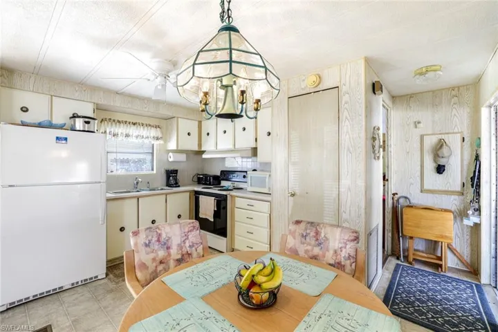 Kitchen featuring white appliances, light countertops, hanging lights, and a textured ceiling