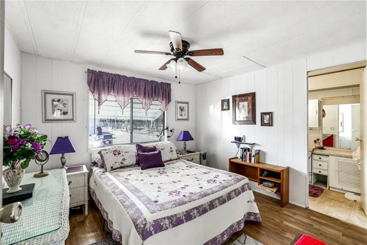 Bedroom with dark wood-style floors, ceiling fan, a textured ceiling, and wooden walls