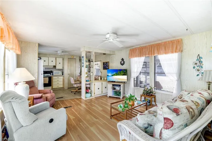 Living area with light wood-type flooring, ceiling fan, and wooden walls
