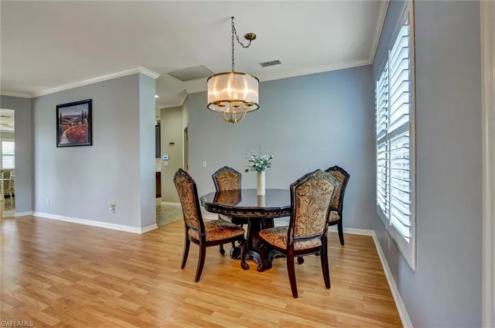 Light wood-finish flooring complements the crown molding and baseboards