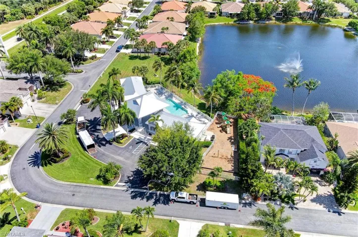 Aerial perspective featuring a residential street, a large body of water with a fountain, and properties with mature landscaping