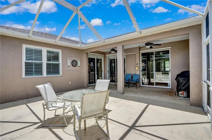 Screened-in patio featuring a concrete slab, multiple sliding glass doors, and two exterior ceiling fans