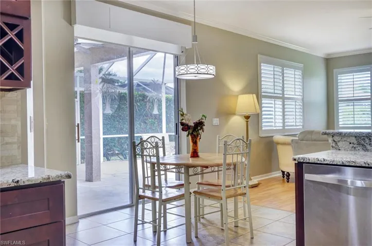 Dining area featuring tile flooring, a contemporary drum pendant light, and sliding glass doors opening to an enclosed patio