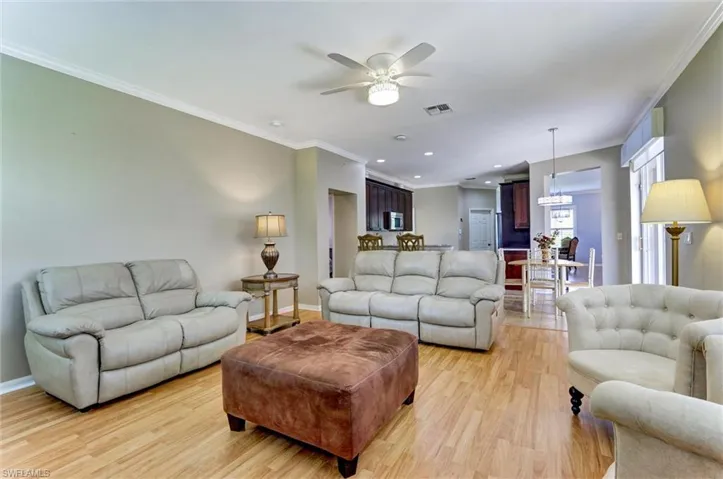 Spacious living area featuring wood-finish flooring and crown molding