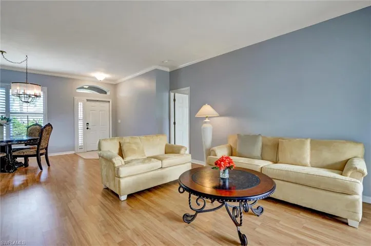 Expansive open-concept room featuring wood-finish flooring, light blue walls, and crown molding