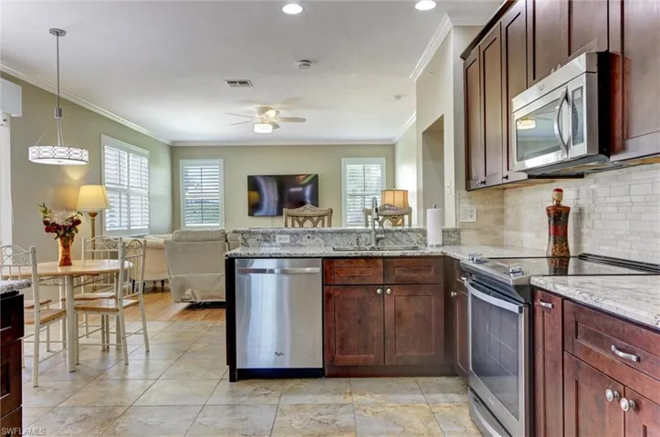Kitchen featuring dark wood-finish cabinetry, stainless steel appliances, granite countertops, and a subway tile backsplash
