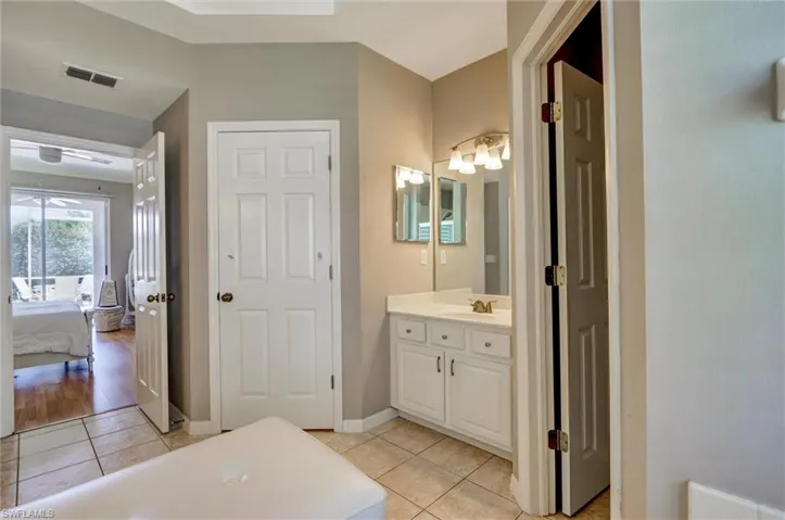 Bathroom vanity with white cabinetry, a single sink, and a multi-bulb light fixture