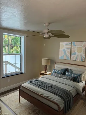 Bedroom featuring wood-finish flooring, a contemporary ceiling fan, and a large window with grid panes