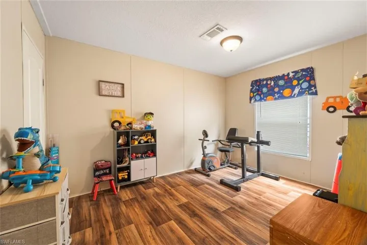 Exercise room with wood-type flooring and a textured ceiling