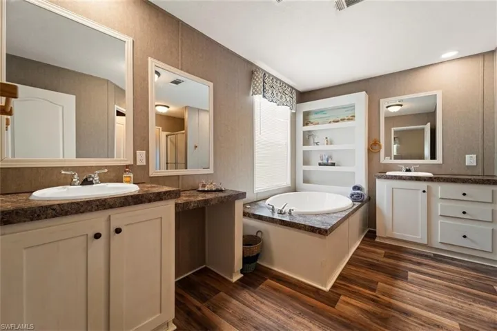 Bathroom featuring a washtub, vanity, hardwood / wood-style flooring, and built in shelves