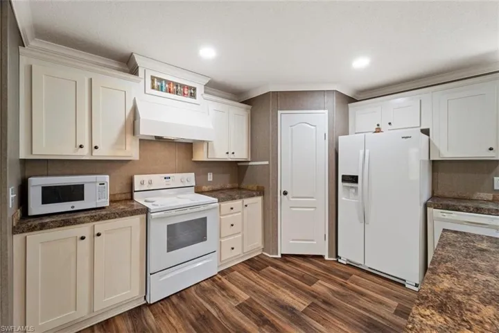 Kitchen featuring white appliances, dark wood-type flooring, and custom exhaust hood