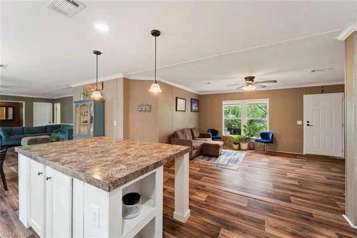 Kitchen featuring a center island, dark wood-type flooring, ornamental molding, white cabinets, and ceiling fan