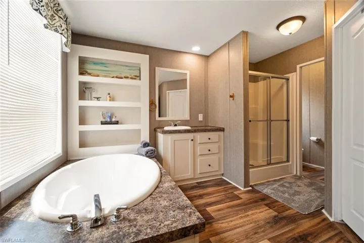 Bathroom featuring independent shower and bath, built in features, a textured ceiling, hardwood / wood-style flooring, and large vanity