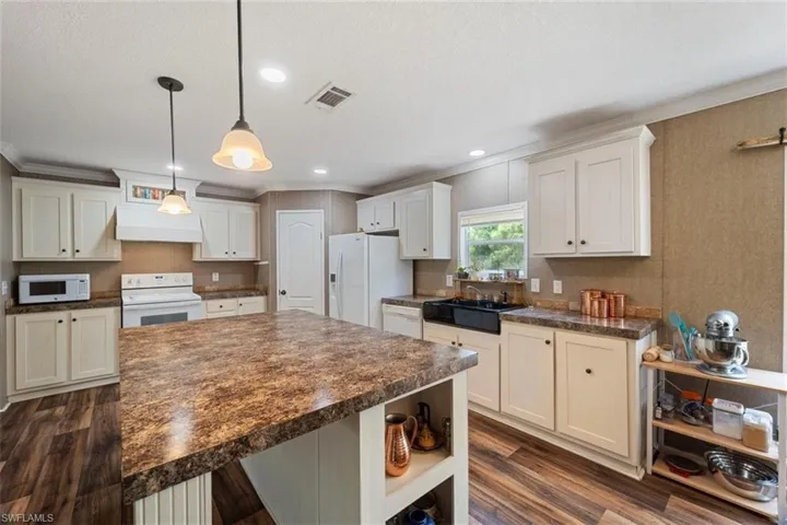 Kitchen featuring ornamental molding, white appliances, premium range hood, dark hardwood / wood-style floors, and decorative light fixtures