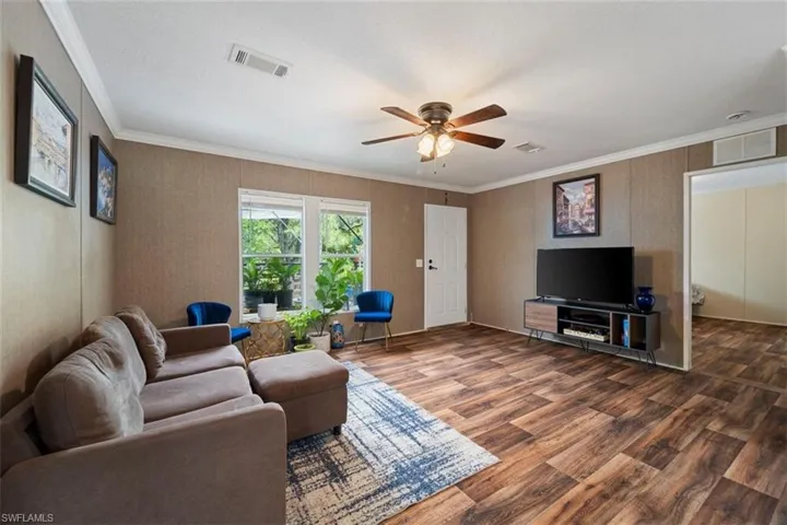 Living room featuring ceiling fan, hardwood / wood-style flooring, and crown molding