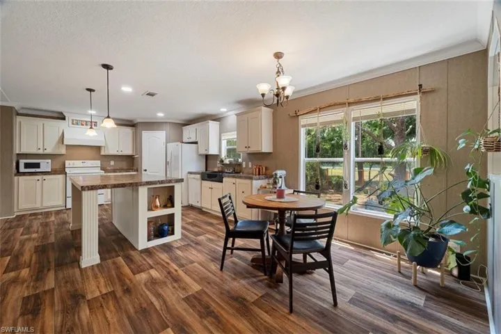 Dining area with crown molding, a textured ceiling, an inviting chandelier, dark hardwood / wood-style floors, and sink