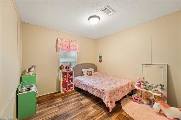 Bedroom with dark hardwood / wood-style flooring and a textured ceiling