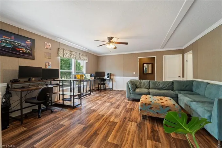 Living room featuring ceiling fan, ornamental molding, and hardwood / wood-style flooring