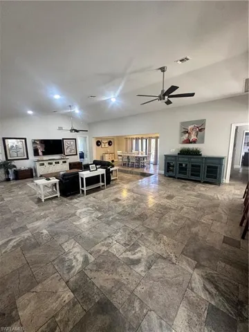 Living room with stone tile flooring, a ceiling fan, and recessed lighting
