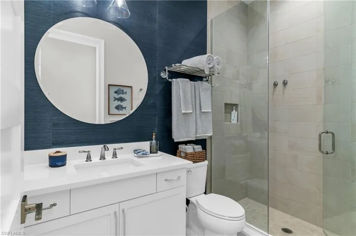 Bathroom with vanity, a shower with shower door, and toilet
