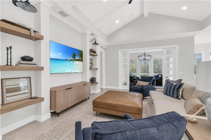 Tiled living room featuring a notable chandelier, high vaulted ceiling, beam ceiling, and a wealth of natural light