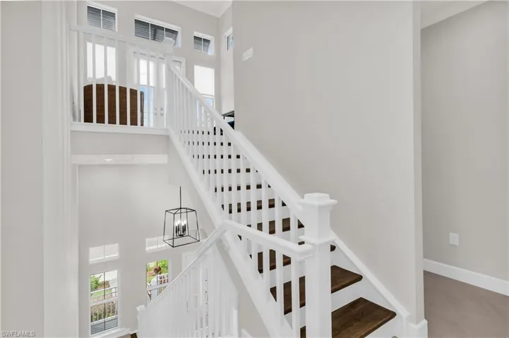 Staircase with carpet flooring, plenty of natural light, a towering ceiling, and an inviting chandelier