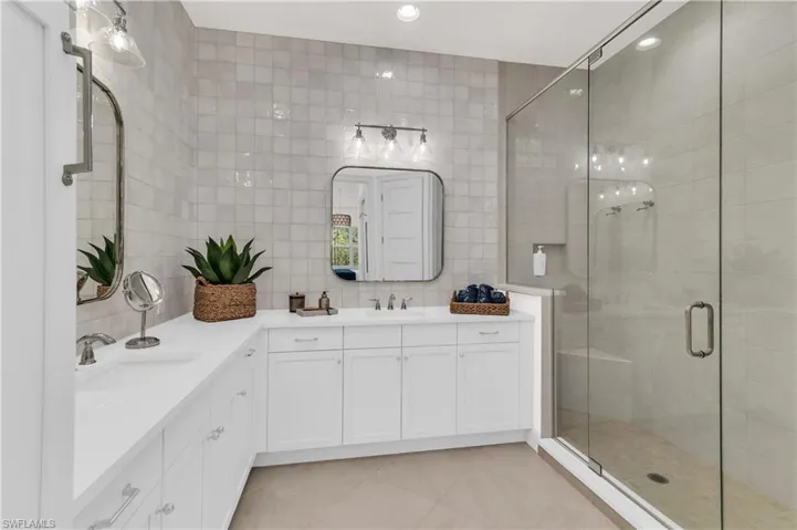 Bathroom with tasteful backsplash, vanity, tile walls, and walk in shower