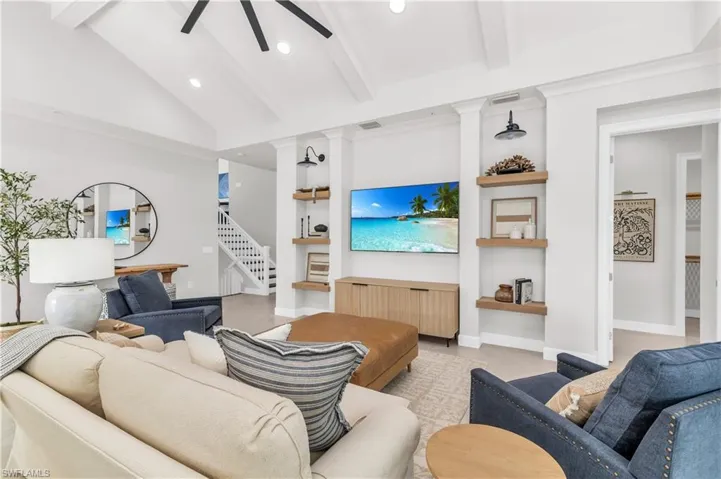 Living room featuring lofted ceiling with beams, built in features, and ceiling fan