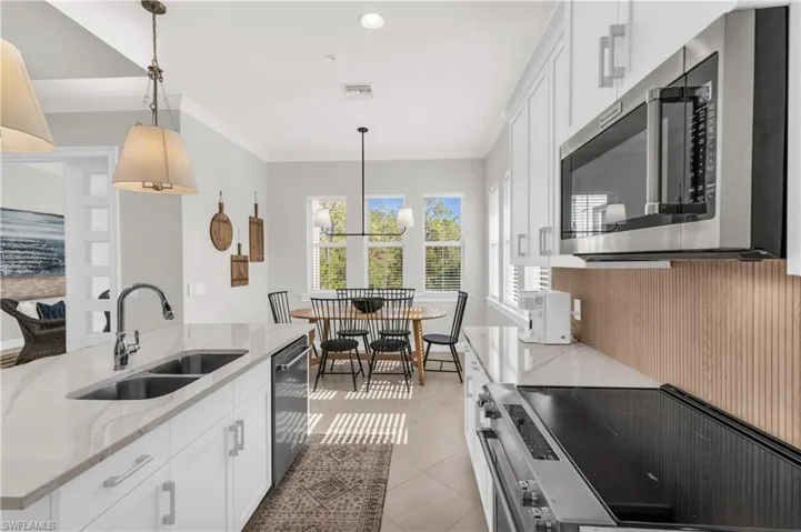 Kitchen featuring light stone counters, stainless steel appliances, white cabinetry, and sink