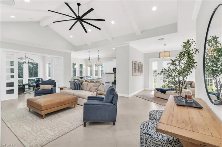 Living room featuring beamed ceiling, light tile patterned floors, high vaulted ceiling, and ceiling fan