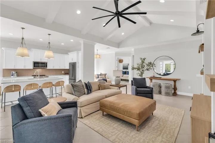 Living room featuring ceiling fan, sink, light tile patterned floors, and lofted ceiling with beams