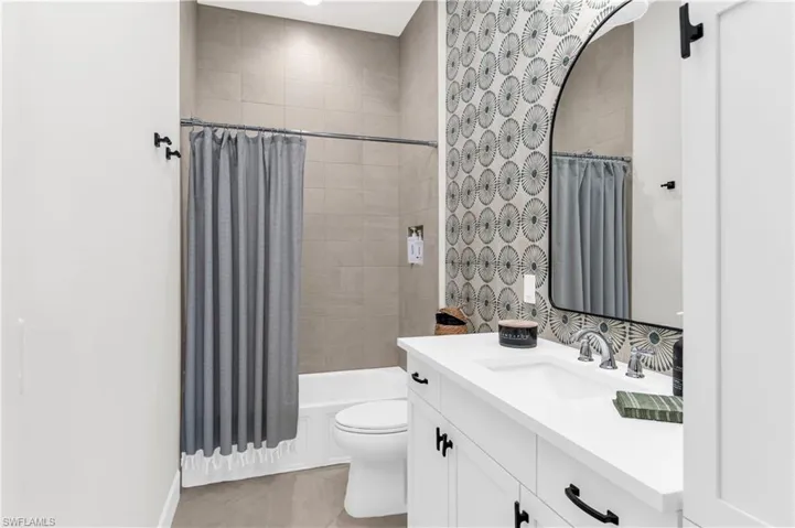 Full bathroom with tile patterned flooring, shower / bath combination with curtain, vanity, and toilet