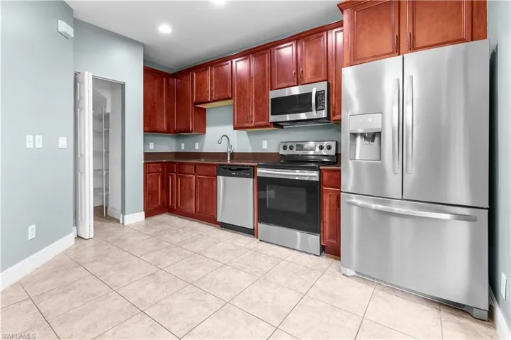 Kitchen featuring light tile patterned floors, sink, and appliances with stainless steel finishes