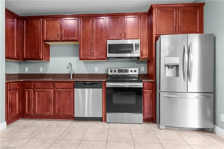 Kitchen featuring light tile patterned floors, stainless steel appliances, and sink