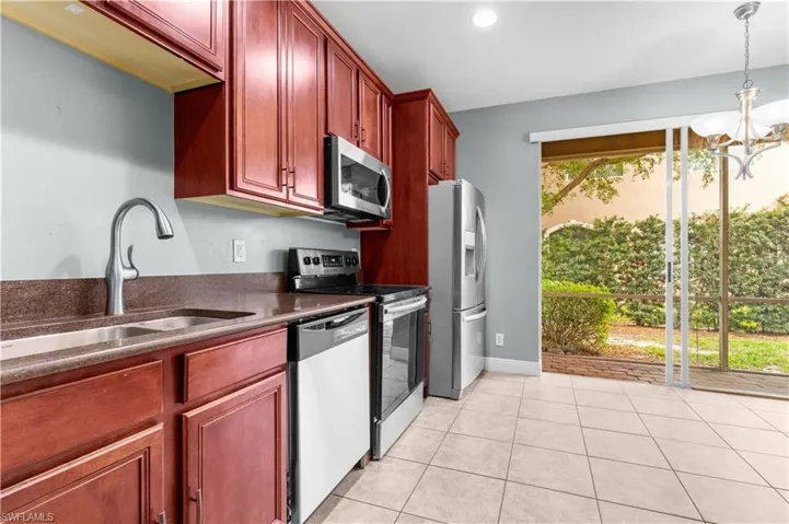 Kitchen featuring sink, an inviting chandelier, decorative light fixtures, light tile patterned floors, and appliances with stainless steel finishes