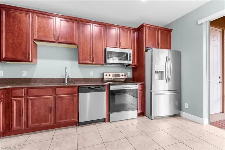 Kitchen with sink, light tile patterned floors, and appliances with stainless steel finishes