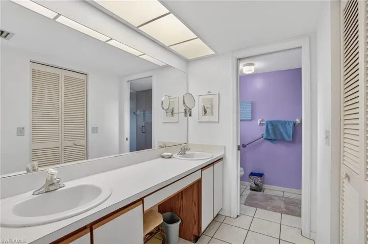 Bathroom featuring a closet, double vanity, and light tile patterned flooring