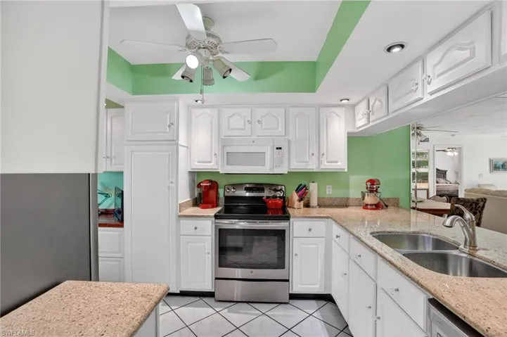 Kitchen featuring ceiling fan, stainless steel appliances, and light stone counters