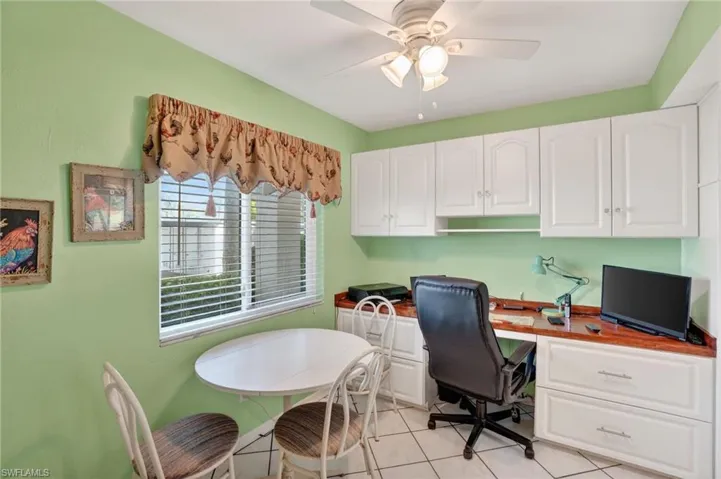 Office area featuring light tile patterned floors, built in desk, and a ceiling fan