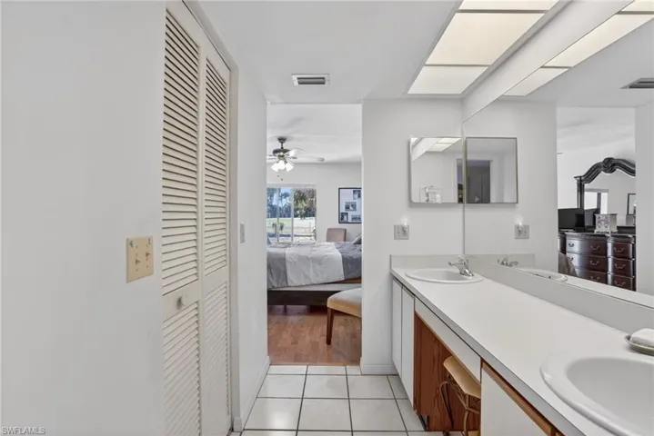 Ensuite bathroom featuring a closet, double vanity, ceiling fan, and light tile patterned flooring