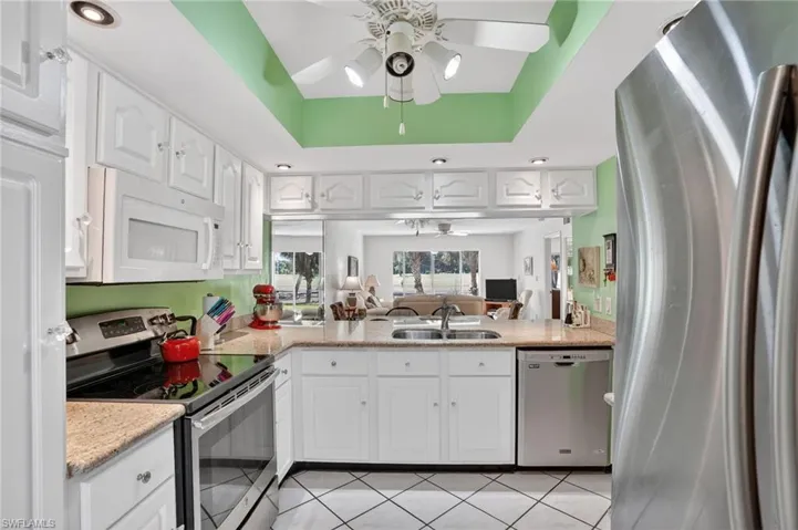 Kitchen featuring a ceiling fan, stainless steel appliances, white cabinets, and light stone counters