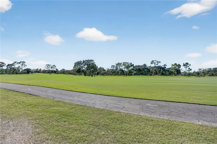 View of property's community featuring view of scattered trees, a yard, and golf course view