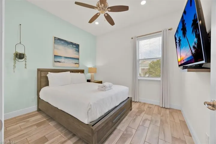 Bedroom with wood tiled floors, ceiling fan, and recessed lighting