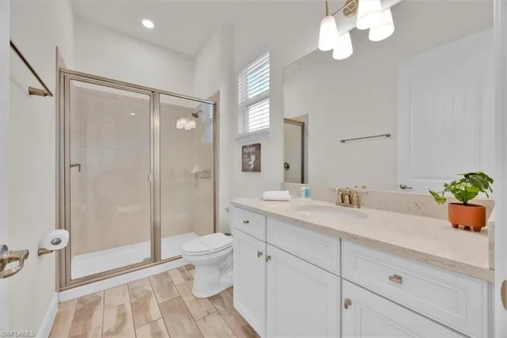 Full bath with a stall shower, vanity, and suspended lighting
