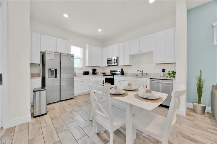 Kitchen with white cabinets, stainless steel appliances, light countertops, recessed lighting, and wood finish floors