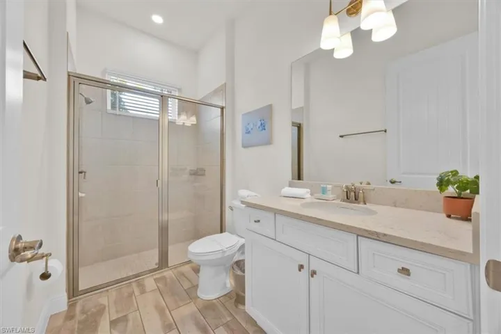 Bathroom with a stall shower, vanity, and wood tiled floors