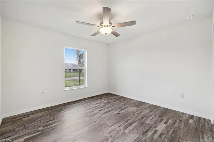 Unfurnished room with ceiling fan and dark hardwood / wood-style flooring